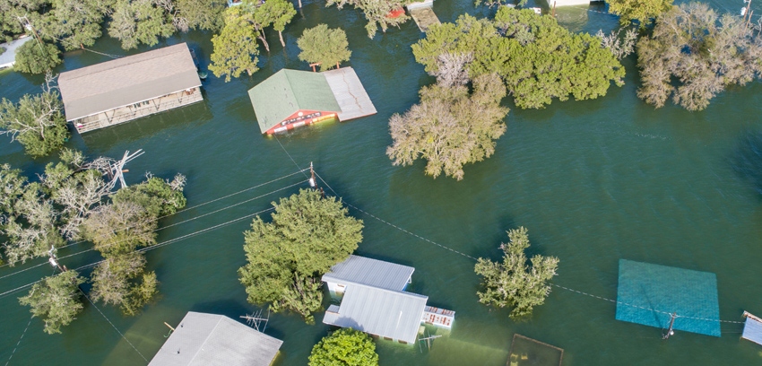 Aerial view of homes and trees partially submerged by floodwaters - https://www.sartori-insurance.com/