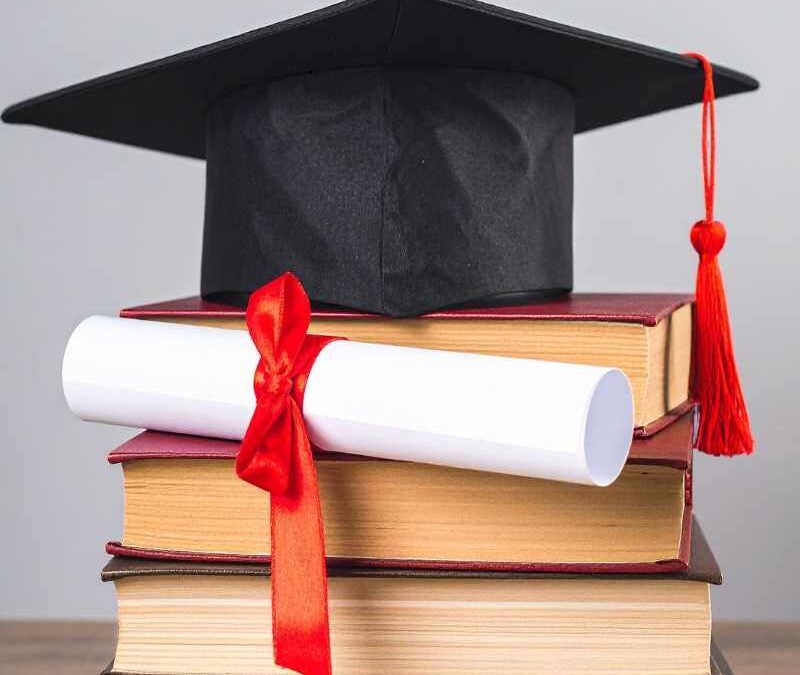 A black graduation cap with a red tassel sits atop a stack of hardcover books - www.sartori-insurance.com